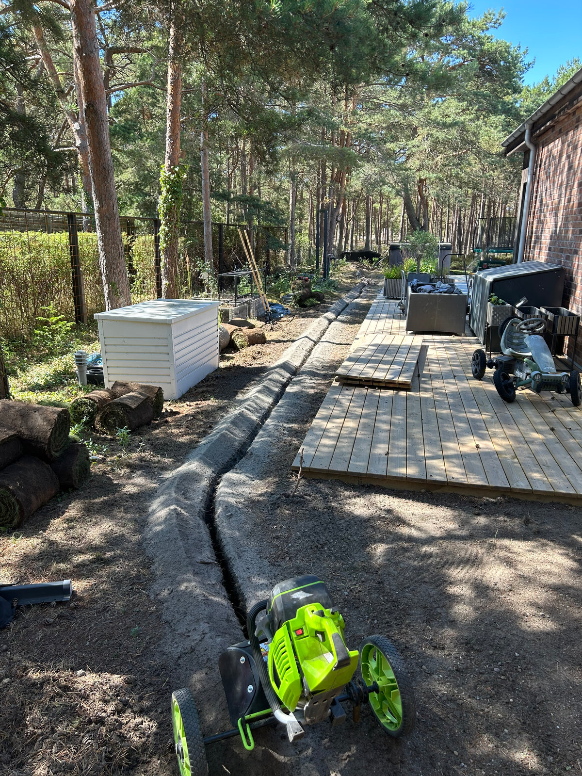 Nygrävt dike längs ett trädäck i en trädgård